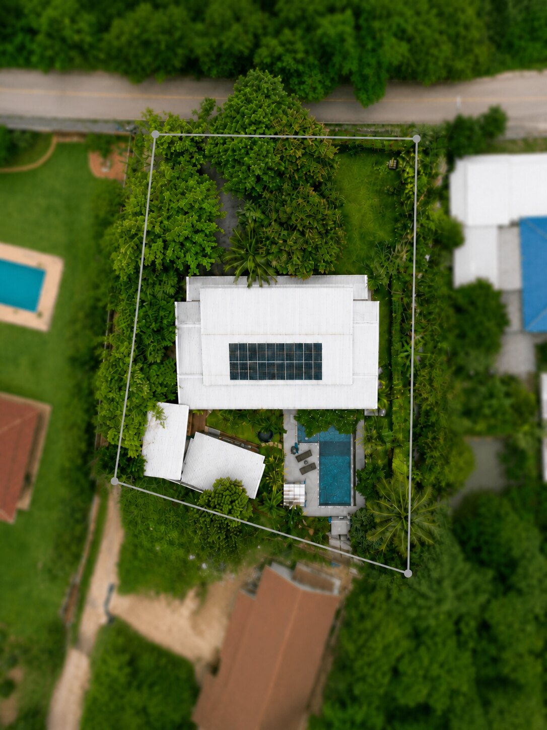 ภาพมุมสูงของ Daisy Land Villa แสดงบ้านหลัก สระว่ายน้ำ บ้านพักแขก และสวนที่เติบโตเต็มที่
